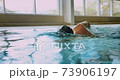 Adaptive amputee professional swimmer front crawl swimming in indoor pool 73906197