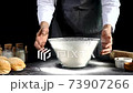 Hand of professional chef man wear grey apron baker bumps glass bowl on table 73907266