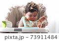 Adorable little funny girl of 12 months eating spaghetti with spoon and drinking water from bottle  73911484