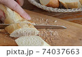 woman cuts long bread close up wooden cutting board in kitchen 74037663