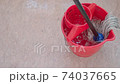 white cotton mop is rinsing in bucket and cleans pink linoleum floor 74037665