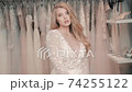 Portrait of woman in wedding dress looking at camera in store boutique. Seductive look of blonde 74255122