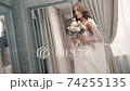 Attractive young woman dressed in wedding dress posing for bridal photo session in studio. 74255135