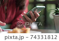 Woman holding smartphone while having breakfast. 74331812