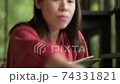 Asian woman using smartphone while reading a book. 74331821