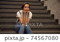 Woman taking a break on the stairs 74567080