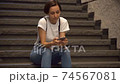 A woman watching a smartphone on the stairs 74567081