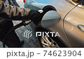 Person Refueling Car's Tank. Gas station worker in workwear refueling luxury car with gasoline holding filling gun at the station 74623904