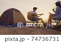 Young adult Asian couple playing guitar and drinking beer beside their tent campsite while sunset with dog. Dolly shot. 74736731