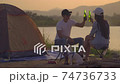 Zoom out shot Young adult Asian couple Cheers and drink beer beside their tent campsite while sunset with Dog 74736733