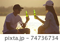 Close up Young adult Asian couple Cheers and drink beer beside their tent campsite while sunset 74736734