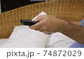 Close-up of a hand with TV remote controller switching TV channels 74872029