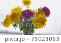 bright yellow and purple flowers in a vase. chrysanthemums on the table near the window. a bouquet of flowers for a holiday. 75023053