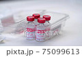 Close-up of doctor's hand pulls out vials with vaccine to treat coronavirus infection from packaging 75099613