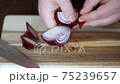 Chef peels red onion, preparing for slicing, male hands, close-up front view 75239657