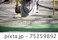 Girl swinging on a swing in the park (slow motion) 75259892