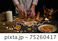 Christmas and new year celebration cooking table with woman hands prepairing gingerbread cookies dow, decor, candle, dry oranges, stars shape tool 75260417
