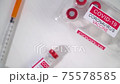 top view syringes and ampoules of coronavirus vaccine on a white wooden table 75578585