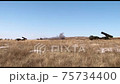 Shooting from rocket launcher mounted on a military vehicle standing in a field. Military equipment in the field, the missile system is firing 75734400