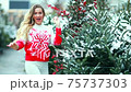 A girl in a red Christmas sweater plays with snow 75737303
