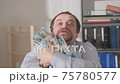 Successful businessman with armful of money in his hands rejoices at financial success in office. 75780577