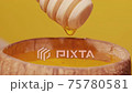 Golden honey pouring from wooden spoon into bowl on yellow background close-up. 75780581