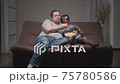 adult man watches TV and eats popcorn in company of doll while sitting on couch in room. 75780586