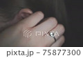 Young caucasian woman ear closeup. She is opening ear by her hand with jevelry rings 75877300