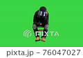 Riot policeman in full uniform sitting having rest and using his smartphone on a Green Screen, Chroma Key. 76047027