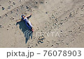 ビーチに散歩しに来た女性の空撮 76078903