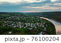 Top view of river and tiny houses in countryside full of green landscapes. 76100204
