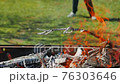 Barbecue fire with someone playing football in the blurry background 76303646