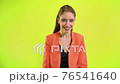 Happy positive woman laughing in space studio on yellow background 76541640