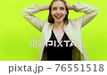 Overjoyed giggling woman celebrating success in space studio on yellow 76551518