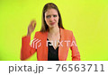 Woman looking at wrist watch in space studio on yellow background 76563711