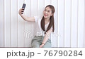 Young Asian beautiful woman taking selfie by her mobile phone on white background 76790284