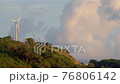 A lonely wind power generator standing on a mountain in a thicket of trees against a background of blue sky and beautiful cumulus clouds. Thailand, Phuket, Naiharn beach. 76806142