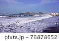 Young surfer is looking at the waves on the beach. 76878652