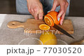 Female hand cut orange, Woman preparing, making citrus and rosemary fresh lemonade in glass on a white table at home, summer drink, detox healthy water. 77030520