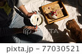 Woman in jeans sitting on the bed, and eating healthy granola bowl during the morning sunlight with cat, breakfast in the bed. 77030521