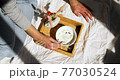 Woman in jeans sitting on the bed, and eating healthy granola bowl during the morning sunlight, breakfast in the bed. 77030524