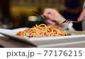 Teenager's hand winding spaghetti on a fork 77176215