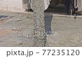 Concrete flowing and pouring from mixer cement truck pours liquid concrete in works road at construction site. 77235120
