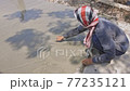 The back view of the worker Adjusting the surface of the concrete road to be smooth and beautiful. An anonymous craftsman doing concrete roads. 77235121