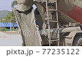 Concrete flowing and pouring from mixer cement truck pours liquid concrete in works road at construction site. 77235122