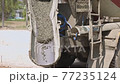 Concrete flowing and pouring from mixer cement truck pours liquid concrete in works road at construction site. 77235124