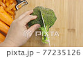 Man hands slice Broccoli on chopping board framed by fresh vegetables on the table - top view, flat lay 77235126