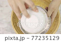 Asian woman sifting flour mixed with cocoa powder through a yellow sieve on the white table. 77235129