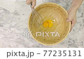 Asian woman sifting flour mixed with cocoa powder through a yellow sieve on the white table. 77235131