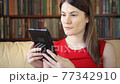 Woman at home reading e-book. Paper vs digital reading, e-books replacing physical print books 77342910